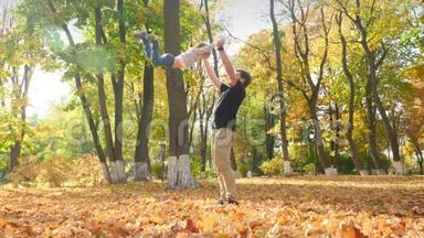 4K慢动作<strong>视频</strong>快乐的年轻父亲在<strong>秋天</strong>公园玩耍，把他的小儿子扔到空中