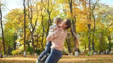 4k视频快乐微笑的母亲举起，抛空，旋转她的孩子在秋天公园