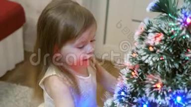 小<strong>女孩</strong>检查<strong>圣诞树</strong>上的花环。 孩子们在孩子们`房间里玩<strong>圣诞树</strong>。 美丽的人造的