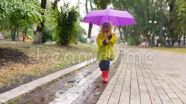 4k慢动作视频：穿着雨衣，穿着橡胶靴的可爱小男孩撑着伞在秋天公园散步