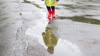 穿着红色<strong>惠</strong>灵顿靴子和黄色雨衣的小男孩在大坑上行走和泼水的慢<strong>动</strong>作视频