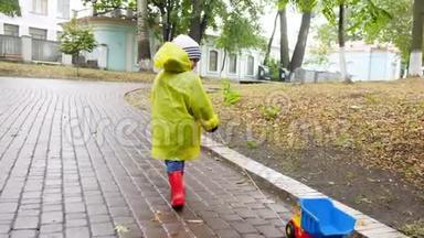 4k<strong>视频</strong>：小男孩穿着红色橡胶靴和黄色雨衣，雨后带玩具卡车在<strong>秋天</strong>公园散步