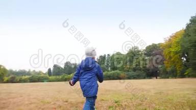 秋天，欢快的小男孩在森林旁边的草地或田野上快速奔跑