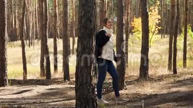 阳光明媚的<strong>秋天</strong>，带着背包在森林里徒步旅行的快乐微笑年轻女子4k<strong>视频</strong>