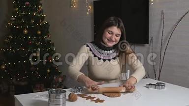 做美味的姜饼男人。 一个年轻的女孩用擀面杖滚面团做姜饼。 双手配合测试