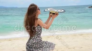 夏天，棕褐色的女人在海滩上度假。欢快的女人穿着<strong>夏装</strong>，戴着草帽坐在沙滩上眺望大海。提姆
