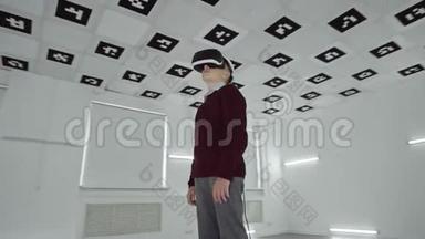 穿棕色毛衣的小男孩正在用虚拟现实耳机<strong>观看视频</strong>。 空荡荡的游戏室充满了白光。 跟踪
