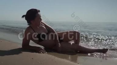 年轻女孩躺在海边和日光浴。 无法辨认的女人在暑假旅行时在海边放松。