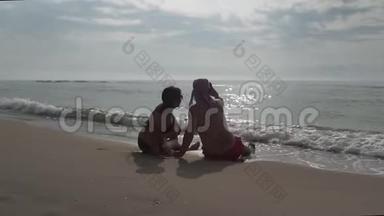 一对夫妇坐在海滩上，在日出时用智能手机拍照。 浪漫夫妇在夏天用智能手机拍照。