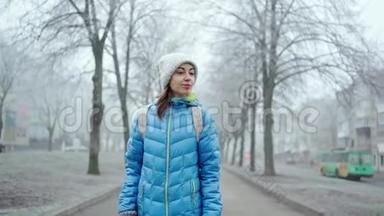 冬天的雾天，穿着<strong>蓝色羽绒服</strong>和羊毛帽的年轻运动女子沿着小巷散步