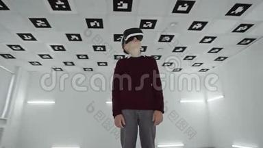 穿着棕色毛衣的小男孩正在用虚拟真人耳机环顾四周。 充满白色霓虹灯的空玩室