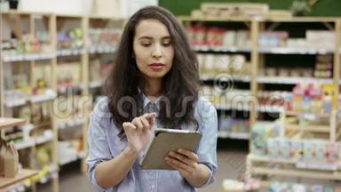女顾客使用平板电脑查看超市的购物清单，做出决定买什么，看