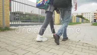 少年女孩和男孩带着背包在人行道上步行上学。 脚的特写。 慢动作录像。