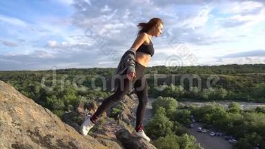 运动的女人在<strong>山崖</strong>上练习瑜伽和体操，有美丽的景观背景。 健康