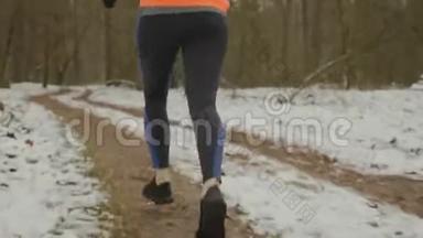 女足在公园里奔跑，靠近后景。 把跑步的腿收起来。 穿着黑色和蓝色的腿和运动鞋的女人慢跑