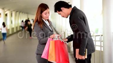 网上购物网站上，女人拿着购物袋在零售购物中心购买产品。 情侣一起买东西