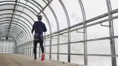 跑步男子在运动服锻炼前三项全能，冲刺玻璃隧道。