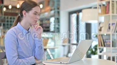 在咖啡馆使用笔记本电脑的体贴的年轻女商人