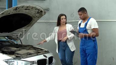 女人用平板电脑向机械师展示汽车的马达