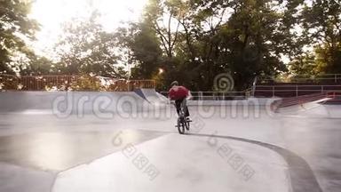 穿着红色T恤和黑色运动裤的酷b mx自行车手，在美丽的夏日里做<strong>360</strong>度旋转魔术