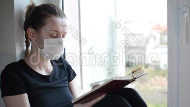 一个戴着医用<strong>口罩</strong>的<strong>年</strong>轻女孩坐在靠近窗户的窗台上看书