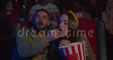 女孩在<strong>电影院</strong>看电影时从男朋友手里偷<strong>爆米花</strong>。 一对夫妇玩得很开心