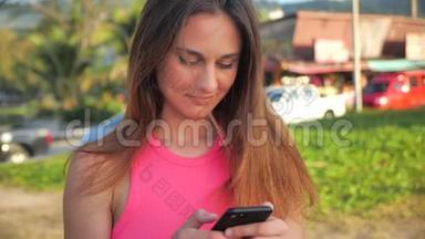 特写一个穿着粉红色短衬衫的迷人女孩的肖像。 她站在背景中的网站棕榈。 可爱是