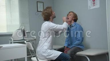 男孩坐在医院的<strong>柜子</strong>里，医生用棍子检查他的嘴