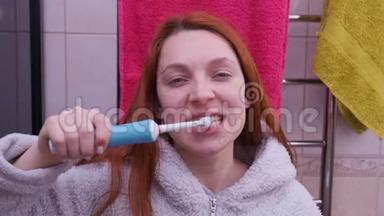 浴室里用电动牙刷刷牙的女人