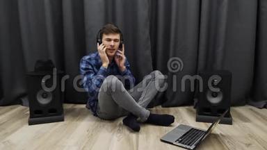 戴着耳机听音乐唱歌的人。 年轻的音乐家坐在地板上用笔记本在耳机里唱歌