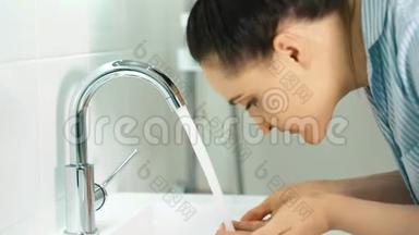 女孩洗了她的脸。 浴室里的女孩早上做水处理。