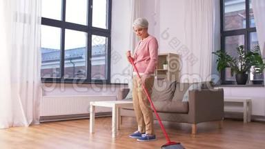 带扫帚扫地板的老妇人