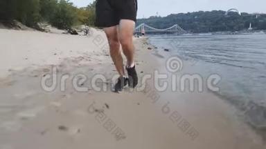 训练有素的肌肉男腿在河滩上跑步。 集中精力的年轻人在河边跑步。 强壮有力的腿在河边慢跑