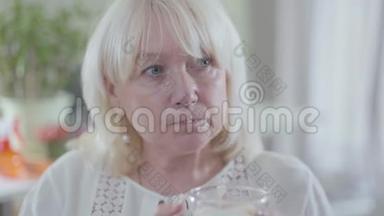 成熟的白种人金发女人的特写脸，灰色的眼睛喝着咖啡，看着远处。 孤独退休人员开支
