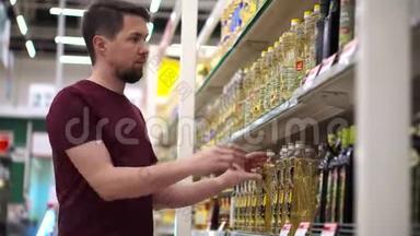 男士购物者在超市的食品过道里拿着带有葵花籽油的瓶子