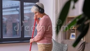 戴着扫把的耳机的老妇人