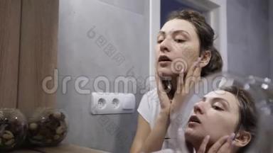 幸福的年轻女人用天然化妆品洁面后，用白色<strong>毛巾擦拭</strong>她的脸。 反思