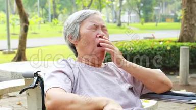亚洲老年妇女有困倦的表情，老年妇女打哈欠，用手捂住张开的嘴，老人感到打哈欠、打瞌睡、困倦