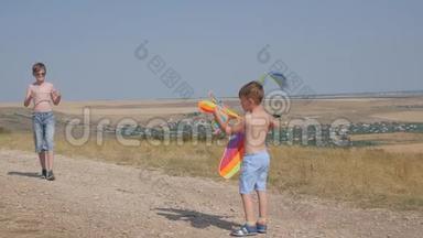 一个男孩带着风筝沿着路跑。 <strong>梦</strong>想<strong>飞翔</strong>，孩子们`游戏.. 蓝天背景下的男孩
