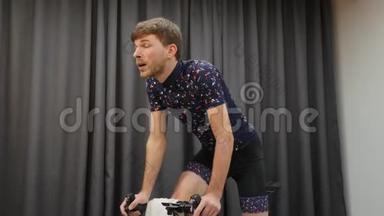 男子骑自行车出马鞍的肖像。 自行车智能培训师概念.. 室内自行车男子硬训练。 骑自行车虚拟社