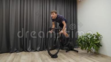 男子密集蹬自行车教练。 男子在室内骑自行车。 室内虚拟自行车。 男子骑自行车冲刺