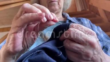 一位年长的老奶奶用针<strong>缝衣服</strong>，双手合拢