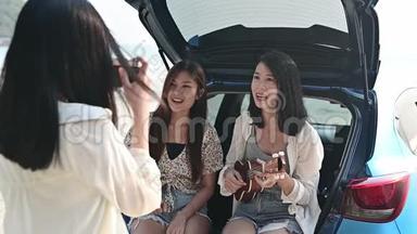 亚洲妇女在海滩上演奏音乐和唱歌。 暑假旅游，泰国.. 放松和娱乐，