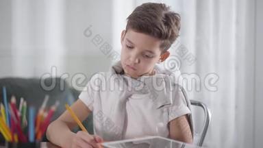 集中白人男孩坐在桌子旁，在笔记本上<strong>画画</strong>或写作的肖像。 <strong>小学生</strong>做作业