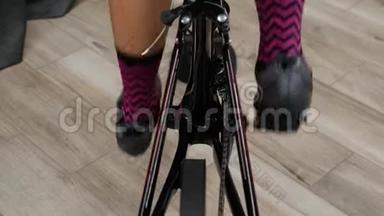 腿蹬着室内智能训练器。 女子双腿硬踏板，同时训练室内固定自行车与踏板和链