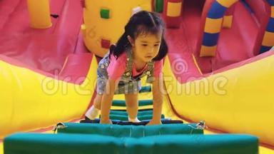 孩子们在庙会上玩空中城堡。 四岁的女孩正在爬坡墙到墙顶。 孩子们喜欢空中城堡