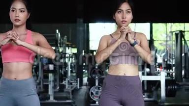 一群穿着运动服的亚洲年轻人在健身房蹲着锻炼