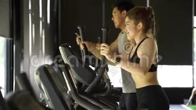 有吸引力的亚洲健身妇女在健身房使用椭圆教练。 健康和减肥的生活方式