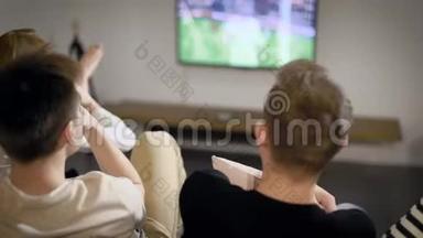 男女青年坐在公寓的沙发上，通过大型<strong>电视观看</strong>足球比赛