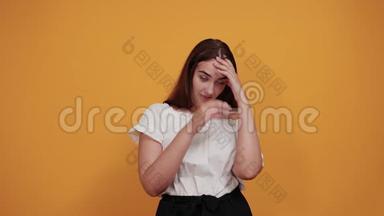 悲伤的女人手牵着头，头痛，头发<strong>飘散</strong>在橙色的墙上